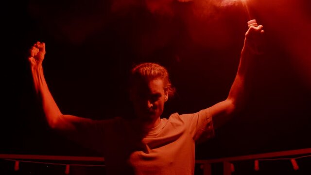 Aggressive man burning signal flare on roof. Football fan standing with fire 