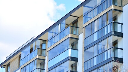 A fragment of modern architecture, walls and glass. Windows and balconies of a residential building against a blue sky. Detail of New luxury house and home complex. Part of city real estate property a