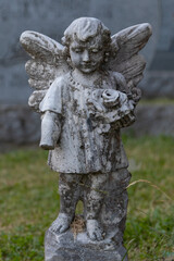 Obraz premium Stone Angel Watching Over a Quiet Cemetery in Quebec, Canada. Years of being out in the elements are shown in the wear on the statute and the missing forearm.