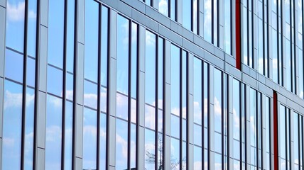 The glazed facade of an office building with reflected sky. Modern architecture buildings exterior background. Clouds sky reflection.