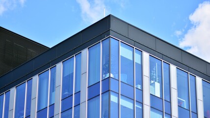 The glazed facade of an office building with reflected sky. Modern architecture buildings exterior background. Clouds sky reflection.