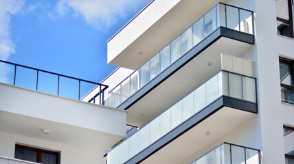 A fragment of modern architecture, walls and glass. Windows and balconies of a residential building against a blue sky. Detail of New luxury house and home complex. Part of city real estate property a