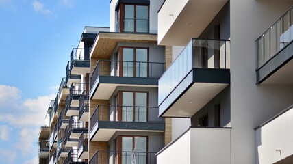 A fragment of modern architecture, walls and glass. Windows and balconies of a residential building against a blue sky. Detail of New luxury house and home complex. Part of city real estate property a