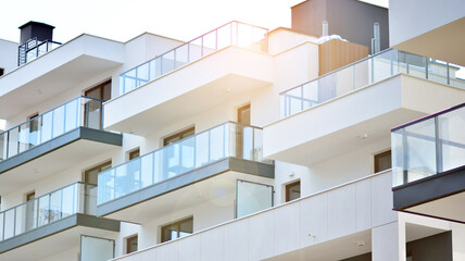 Detail of new luxury house and home complex. Glass surface with sunlight. Rising sun on the horizon. Part of modern residential apartment with flat building exterior. 