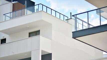 A fragment of modern architecture, walls and glass. Windows and balconies of a residential building against a blue sky. Detail of New luxury house and home complex. Part of city real estate property a