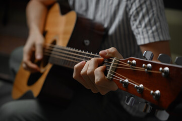 Man playing acoustic guitar, cover for online courses, learning at home.