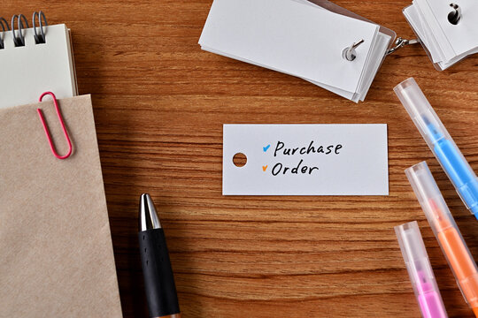 There is word book and colored pens with the word Perchase Order written on it with notebook and envelope