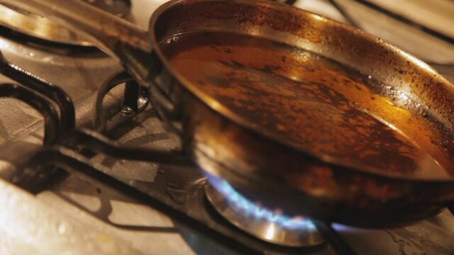 Frying pan with very hot oil preparing for frying. A risk for heart disease such as heart attack, clogged arteries and cardiac arrest, as well as an increased risk of cancer and other diseases.