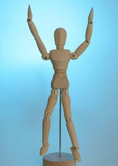 Painting Sketch Wooden Man Model Artist Movable Limbs Doll Wood Carving Man Wooden Toy Art Draw Action Figure Mannequin Kids Toy puppet with two arms up, on a reflective mirrored blue floor light