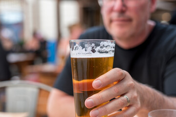 Closeup of a man's hand holding a cold glass of beer