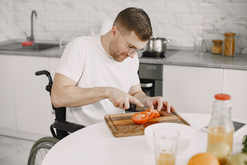Disabled Young Man in Wheelchair Preparing Food In Kitchen