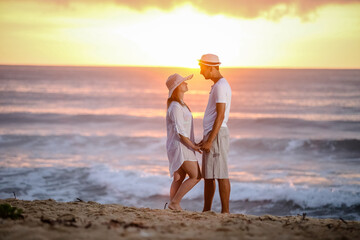 Lindo Casal na praia com fundo do por do sol.