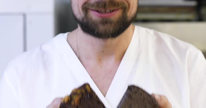 Fresh black bread. Close-up. Delicious frame. A man baker is sniffing two loaves of black freshly baked bread.