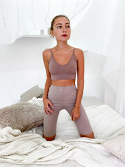 Beautiful young woman in bed wearing sports bra and knee length leggings
