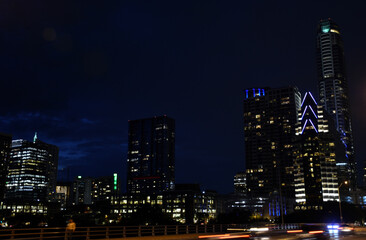 Fototapeta na wymiar Night skyline over bridge with passing cars and lighted buildings