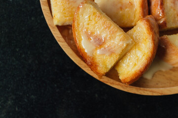 Thai Condensed Milk Toast served on wooden plate on black table.