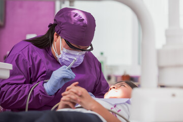 Dentista mexicana, chequeo médico de la cavidad bucal de la paciente con instrumentos dentales - obrazy, fototapety, plakaty