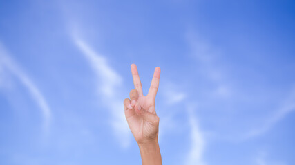 Slim hand woman two fingers showing isolated on blur image of blue sky. strength, new beginning, victory, encouragement, The fight, new hope, success symbols concept.