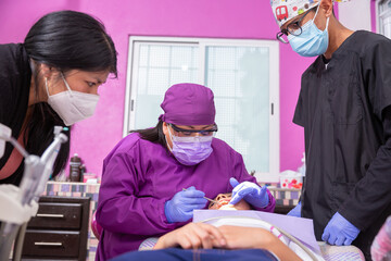 Mexican Pediatric Dentist Explaining To Young Patient And Her Mother