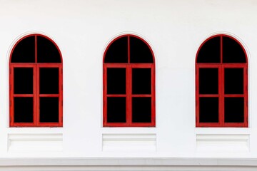 Three bright red wooden windows and white cement wall