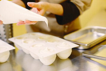 Confectioner works with a pastry bag