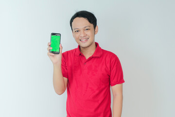 Smart Young asian man is happy and smiling when showing green screen of smartphone in studio background