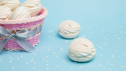 Wicker basket with fresh meringue and jam on a blue background.