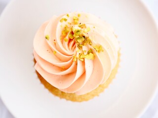 Pretty pink frosted cupcake minimally styled in the centre of a white plate