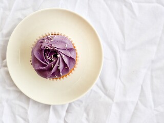 Purple cupcake minimally styled on a white bright textured background