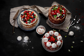 Assorted delicious and colorful homemade cakes with different type of filling on black background.