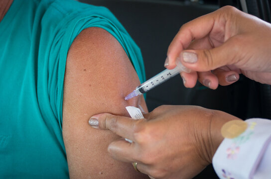 hand holding a syringe and injecting a COVID-19 vaccine