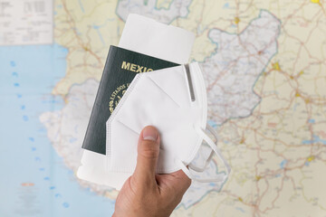 Mano de hombre sosteniendo pasaporte mexicano con cubrebocas