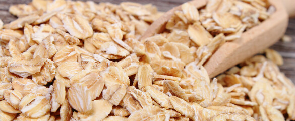Oat flakes with wooden spoon as source dietary fiber. Wooden background