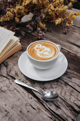 Cappuccino coffee latte art, Warm coffee in mug on white plate with Dried flowers background.