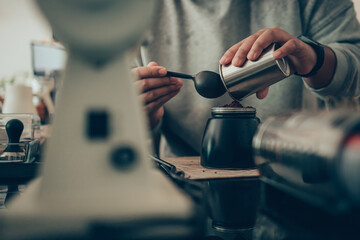 Barista measure coffee powder and brewing black moka coffee using moka coffee maker.