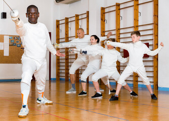 African American happy cheerful fencer practicing effective fencing techniques in training room