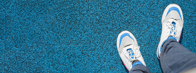 Man in sports sneakers for running, standing on a rubberized, blue covering outside. Close-up, top...