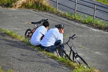 親子でサイクリングして肩並べて休んでいる後ろ姿