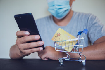 Man in medical mask using smartphone for online shopping in home