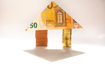 House made of brick and coin stacks with a 50 euro note as a roof. Home loan real estate for mortgage concept