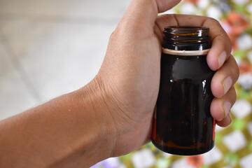 hand holding Brown Drug or medicine Bottle closeup
