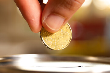 A female hand about to introduce a coin in a money box. Save money concept banner.