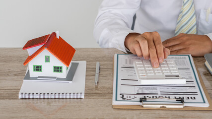 House type real estate agent and calculator with contract documents on the table in the office.
