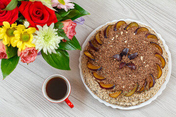 Obraz na płótnie Canvas Chocolate cake decorated with plums and cup of coffee