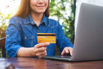 Closeup image of a woman holding credit cards while using laptop computer for online shopping