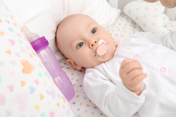 Cute little baby with bottle of water in crib, closeup