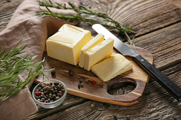 Board with fresh butter and knife on wooden background