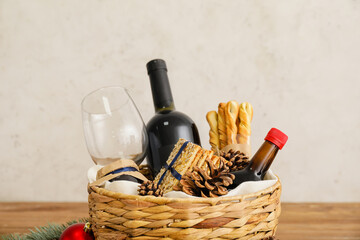 Gift basket with products and Christmas decor on light background