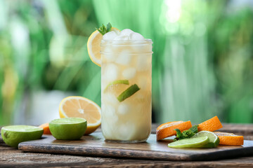 Glass of cold tea with mint and citrus fruits on table outdoors