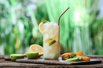 Glass of cold tea with mint and citrus fruits on table outdoors